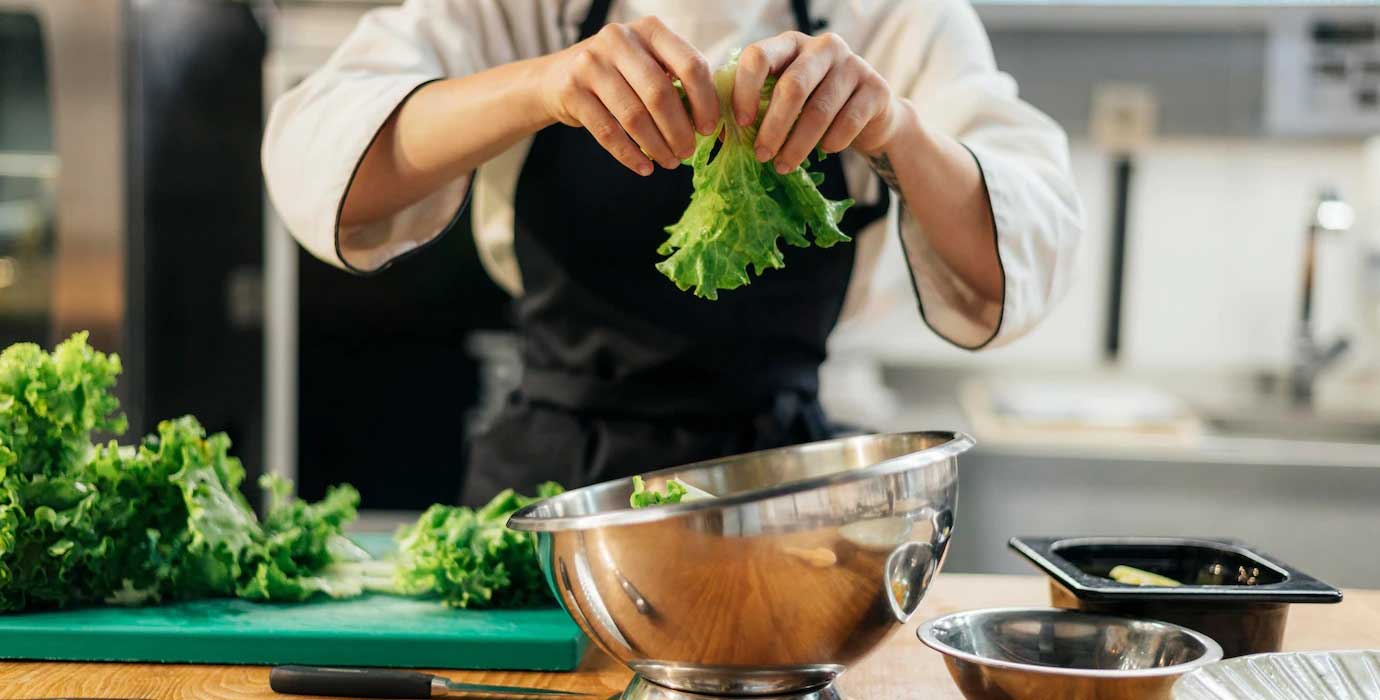 front-view-female-chef-tearing-salad-kitchen_23-2148763183